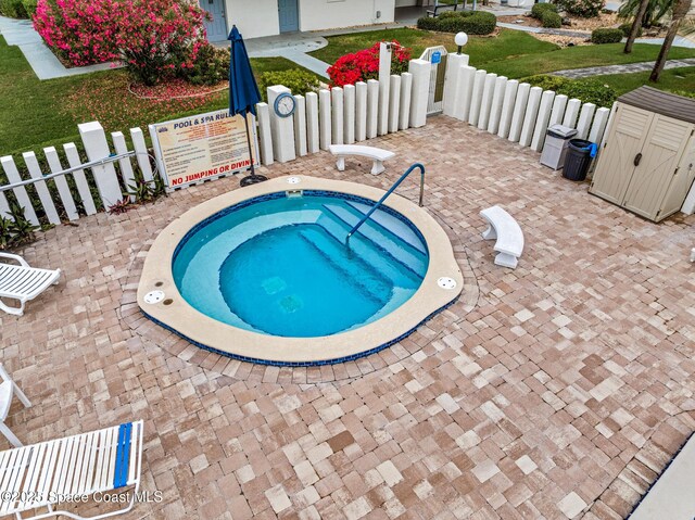 3165 N Atlantic Ave Unit C206, Cocoa Beach, FL 32931 - view of swimming pool with a community hot tub, a storage unit, an outbuilding, and fence