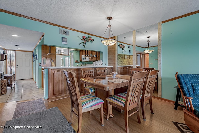 3165 N Atlantic Ave Unit C206, Cocoa Beach, FL 32931 - dining space with crown molding, a textured ceiling, light wood finished floors, and baseboards