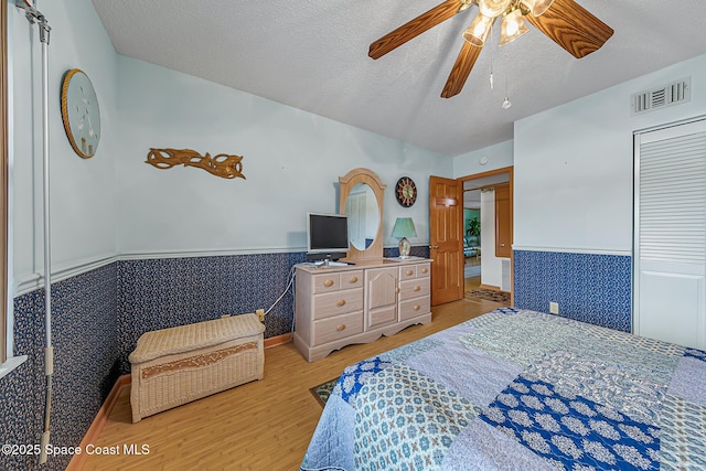 3165 N Atlantic Ave Unit C206, Cocoa Beach, FL 32931 - bedroom with a wainscoted wall, light wood-type flooring, a textured ceiling, ceiling fan, and a closet