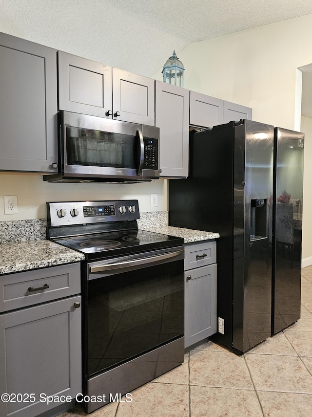 6630 Cecil Rd, Cocoa, FL 32927 - kitchen featuring stainless steel appliances, gray cabinets, light tile patterned floors, lofted ceiling, and a textured ceiling