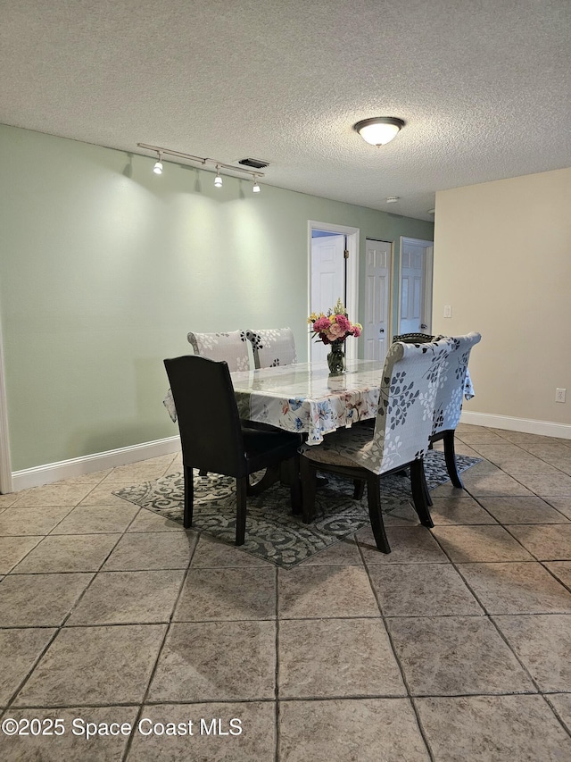 6630 Cecil Rd, Cocoa, FL 32927 - dining space with a textured ceiling, rail lighting, and light tile patterned floors