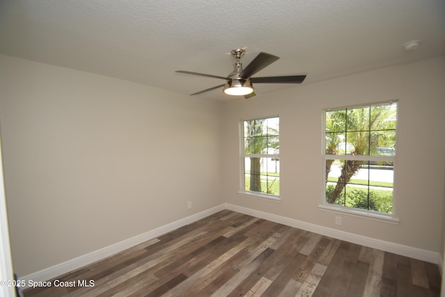 spare room with baseboards, dark wood finished floors, a ceiling fan, a textured ceiling, and a smoke detector