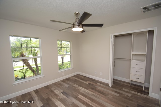 unfurnished bedroom with dark wood-type flooring, baseboards, a closet, a textured ceiling, and a ceiling fan