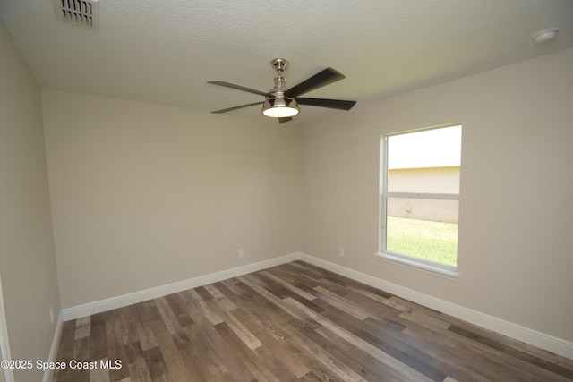 spare room featuring wood finished floors, baseboards, a ceiling fan, a smoke detector, and a textured ceiling