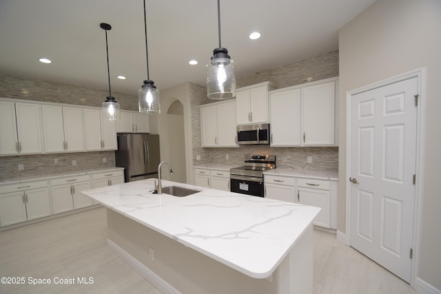 kitchen with stainless steel appliances, a sink, decorative backsplash, arched walkways, and recessed lighting