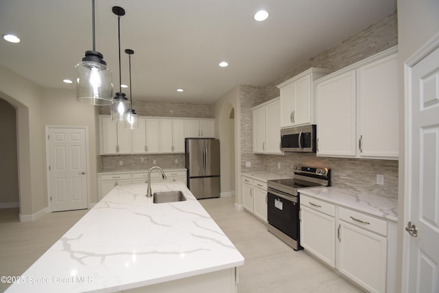kitchen featuring stainless steel appliances, arched walkways, a sink, backsplash, and recessed lighting