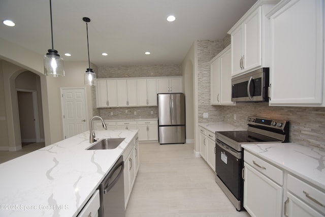 kitchen with stainless steel appliances, a sink, arched walkways, white cabinets, and recessed lighting