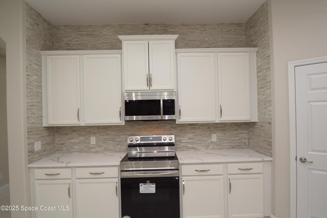 kitchen with stainless steel appliances, white cabinets, backsplash, and light stone countertops