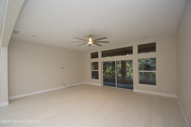 spare room with light wood-style flooring, a ceiling fan, and baseboards