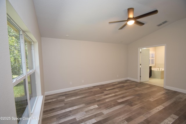 unfurnished bedroom featuring lofted ceiling, wood finished floors, ensuite bath, baseboards, and ceiling fan