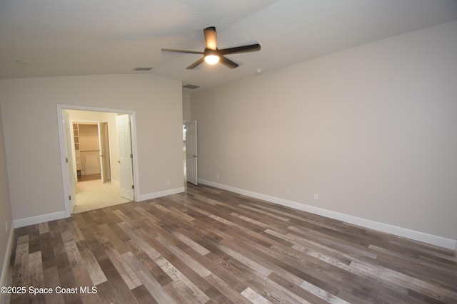 empty room with a ceiling fan, wood finished floors, lofted ceiling, and baseboards