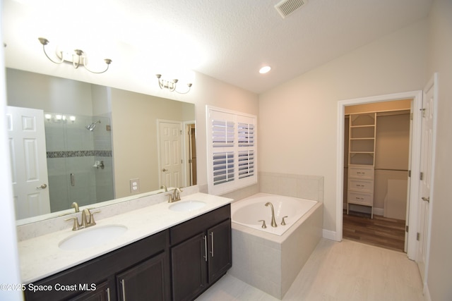 full bath with a shower stall, a bath, a spacious closet, double vanity, and recessed lighting