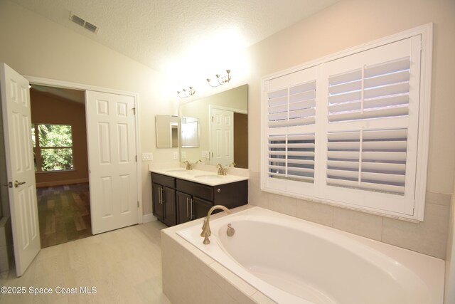 full bathroom featuring lofted ceiling, a bath, wood finished floors, and double vanity