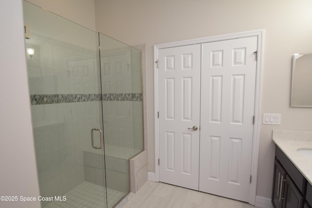 bathroom with a stall shower, vanity, and wood finished floors