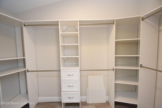 spacious closet with wood finished floors and vaulted ceiling