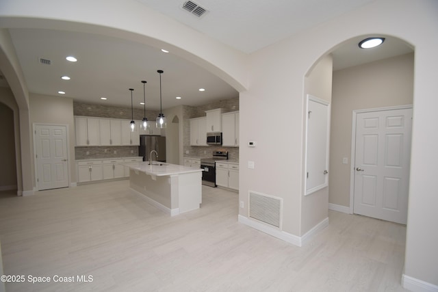 kitchen with stainless steel appliances, light wood-style floors, backsplash, white cabinetry, and recessed lighting