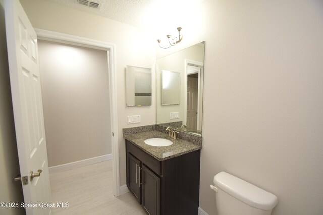 bathroom featuring toilet, vanity, baseboards, and wood finished floors