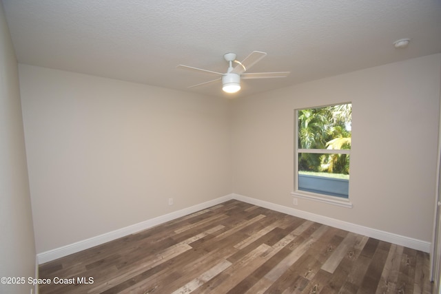 spare room featuring ceiling fan, dark wood finished floors, baseboards, a smoke detector, and a textured ceiling