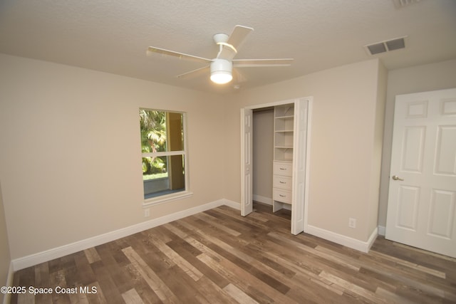 unfurnished bedroom with wood finished floors, baseboards, a textured ceiling, a closet, and a ceiling fan