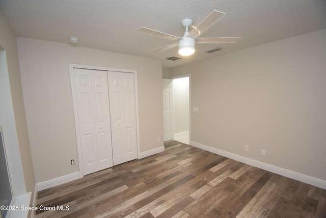unfurnished bedroom with wood finished floors, a closet, and baseboards