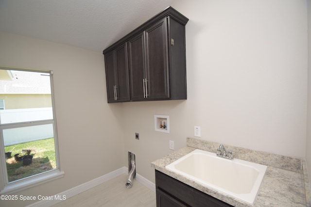 laundry area with electric dryer hookup, hookup for a washing machine, cabinet space, light wood-style floors, and baseboards
