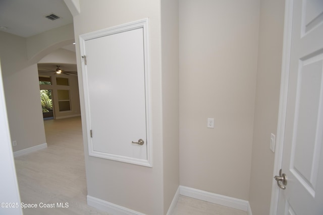 hallway featuring arched walkways and baseboards
