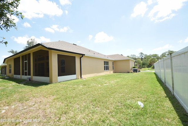 rear view of house featuring a sunroom, stucco siding, and a shingled roof