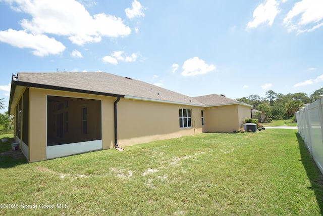 back of house with central air condition unit, a sunroom, and stucco siding