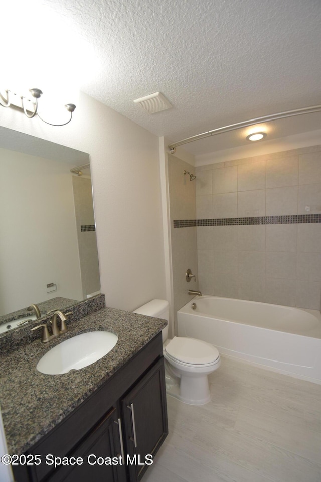 full bathroom featuring shower / washtub combination, toilet, a textured ceiling, vanity, and wood finished floors