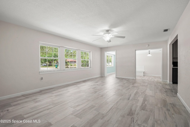 spare room featuring ceiling fan, light wood-type flooring, a textured ceiling, and baseboards