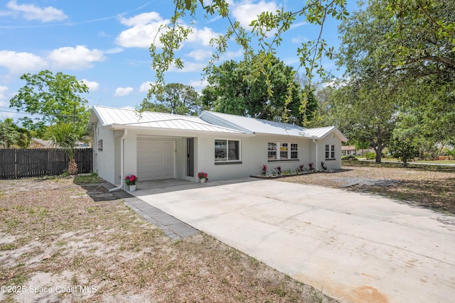 ranch-style home with a standing seam roof, driveway, a garage, fence, and metal roof