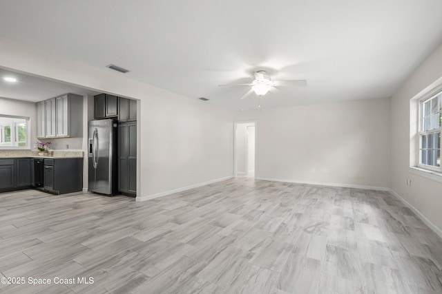 unfurnished living room featuring ceiling fan, plenty of natural light, light wood-type flooring, and baseboards