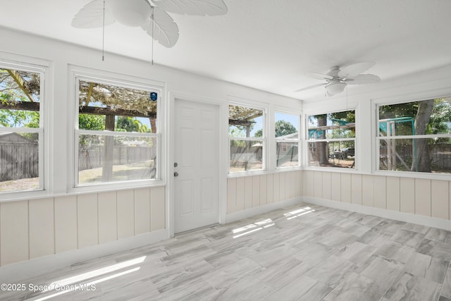 unfurnished sunroom featuring ceiling fan and plenty of natural light