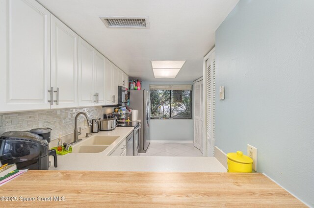 kitchen with a sink, appliances with stainless steel finishes, decorative backsplash, baseboards, and light countertops