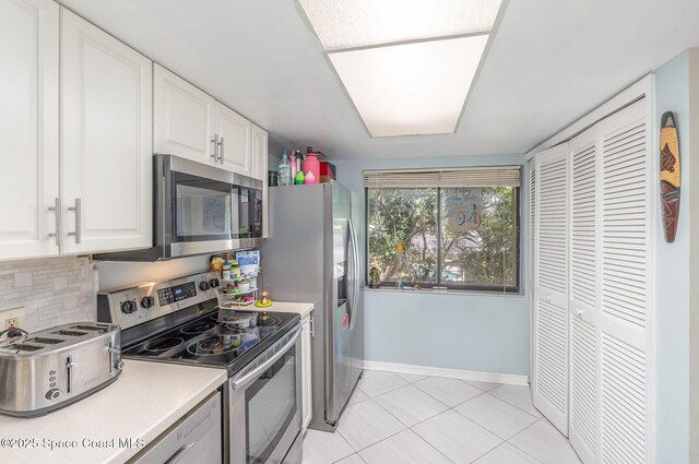 kitchen featuring stainless steel appliances, white cabinets, decorative backsplash, baseboards, and light tile patterned floors