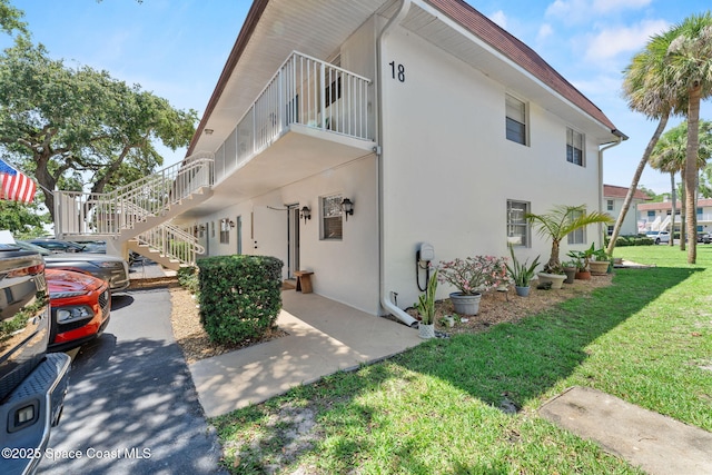 261 Cape Shores Cir Unit 18-E, Cape Canaveral, FL 32920 - view of side of home featuring stucco siding, stairs, and a lawn