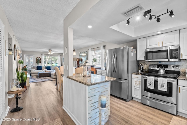 261 Cape Shores Cir Unit 18-E, Cape Canaveral, FL 32920 - kitchen featuring appliances with stainless steel finishes, light wood finished floors, stone countertops, a textured ceiling, and a ceiling fan