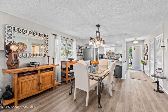 261 Cape Shores Cir Unit 18-E, Cape Canaveral, FL 32920 - dining space with light wood-type flooring, a chandelier, and a textured ceiling