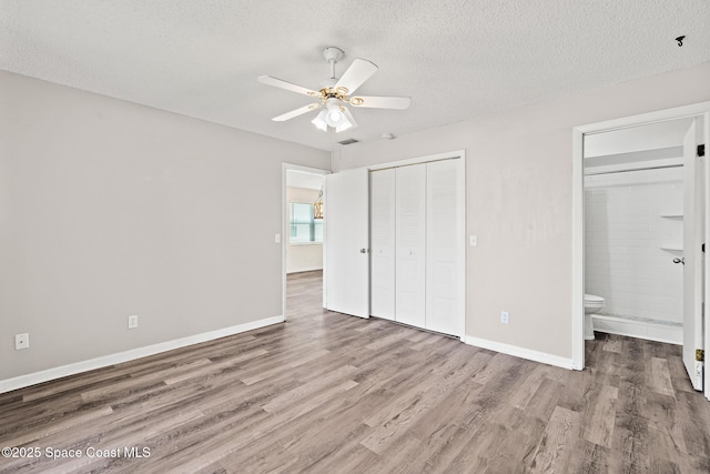 7201 Ridgewood Ave Unit 23, Cape Canaveral, FL 32920 - unfurnished bedroom with wood finished floors, a textured ceiling, baseboards, ensuite bathroom, and a closet