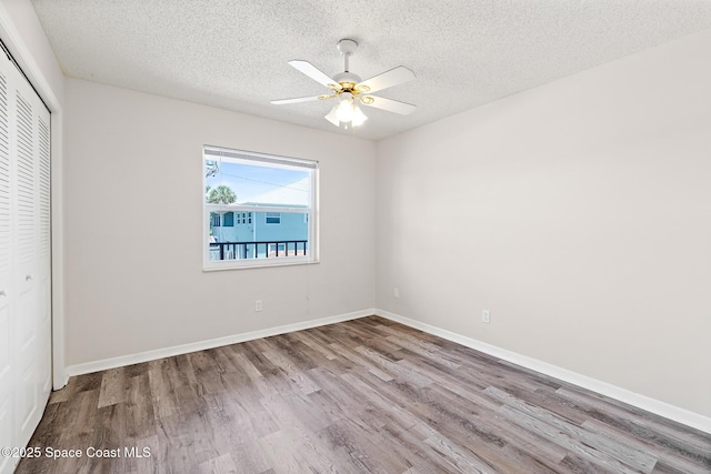 7201 Ridgewood Ave Unit 23, Cape Canaveral, FL 32920 - unfurnished bedroom featuring wood finished floors, a closet, a textured ceiling, baseboards, and ceiling fan