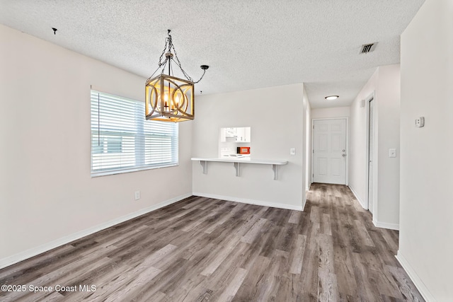 7201 Ridgewood Ave Unit 23, Cape Canaveral, FL 32920 - unfurnished dining area with a textured ceiling, wood finished floors, a chandelier, and baseboards