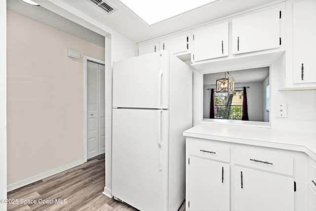 7201 Ridgewood Ave Unit 23, Cape Canaveral, FL 32920 - kitchen with freestanding refrigerator, light countertops, light wood-type flooring, and white cabinets