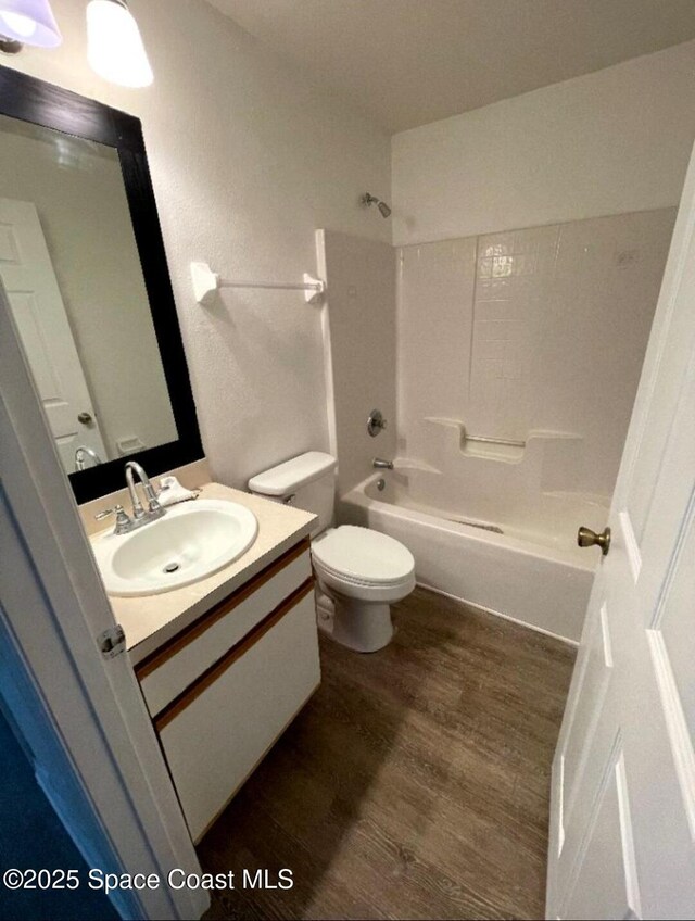 409 Bougainvillea St NW, Palm Bay, FL 32907 - bathroom featuring wood finished floors, vanity, washtub / shower combination, and toilet