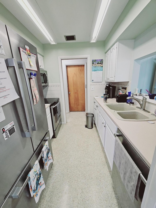 7181 Blue Shore Rd, Grant, FL 32949 - kitchen with appliances with stainless steel finishes, a sink, white cabinetry, light countertops, and tile walls