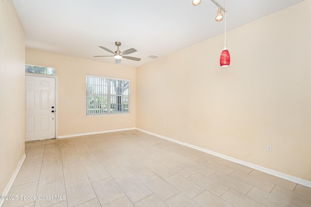 spare room with ceiling fan, healthy amount of natural light, and baseboards