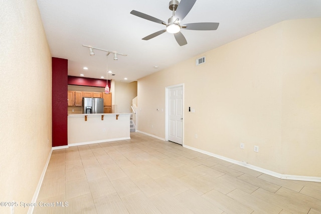 unfurnished living room with ceiling fan, rail lighting, stairs, and baseboards