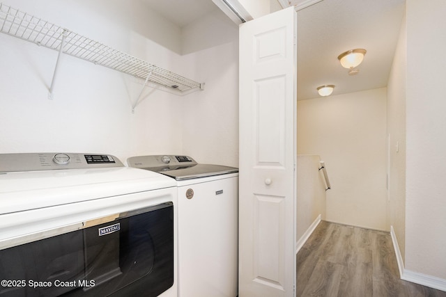 laundry area featuring washer and clothes dryer, light wood finished floors, and baseboards