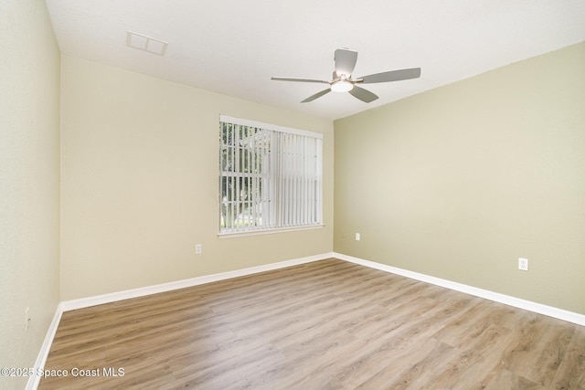 spare room with light wood-type flooring, a ceiling fan, and baseboards