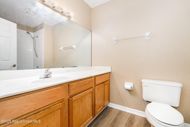 full bath with wood finished floors, toilet, vanity, baseboards, and a tile shower