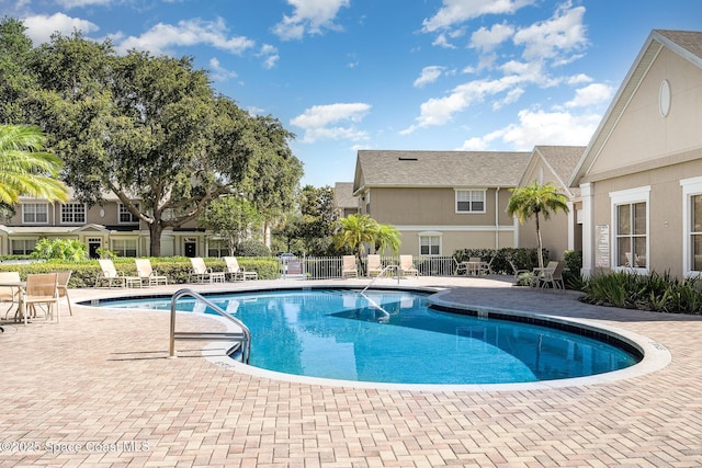 community pool with a patio and fence